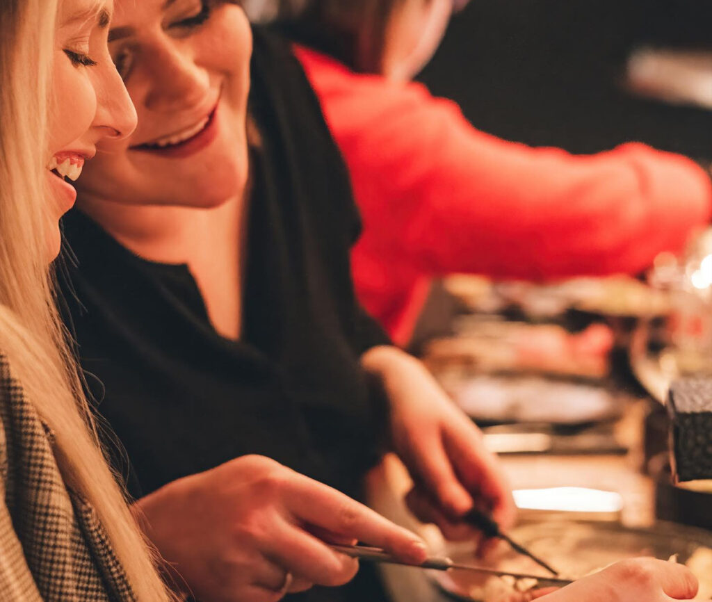Zakenlunch of diner in ons sfeervol fondue restaurant, met collega's die rond een dampende fonduepot zitten in een moderne setting.