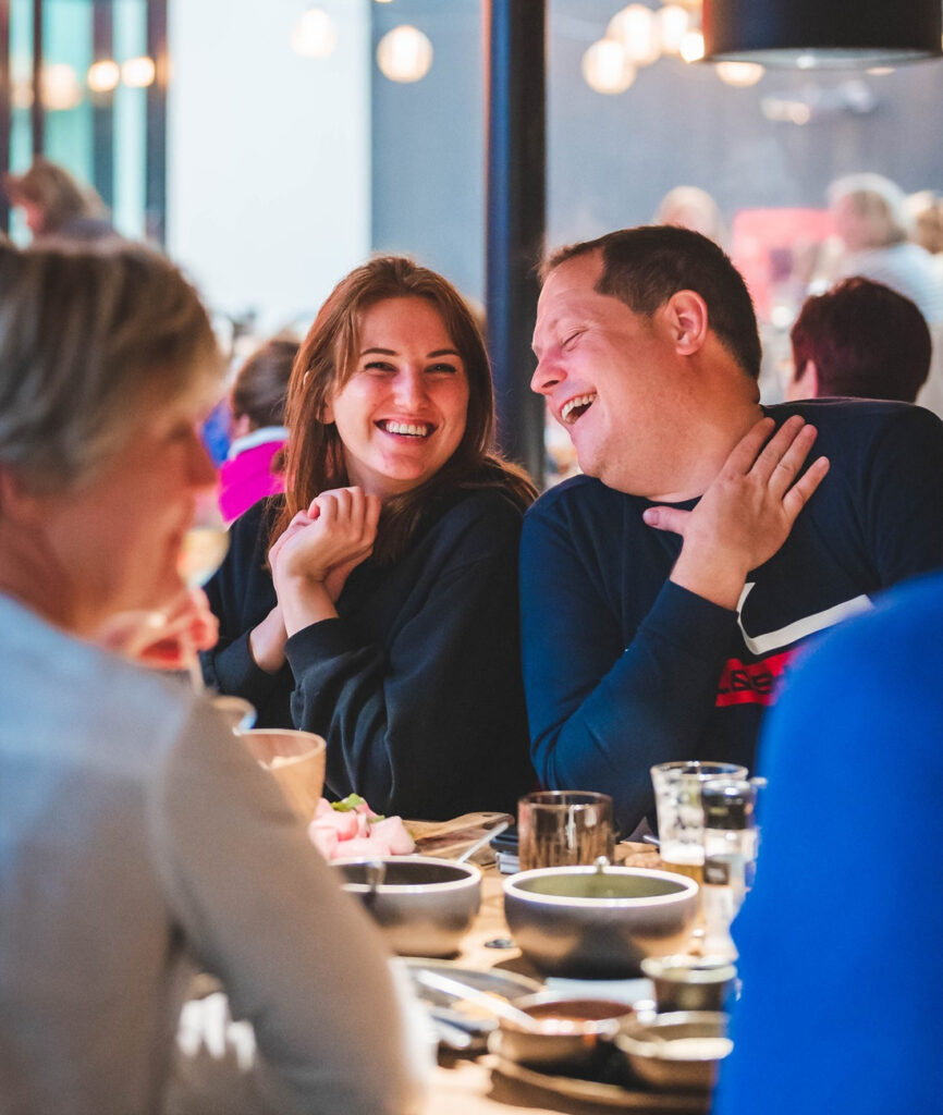 Lachende vrienden tijdens fondue etentje op ons terras