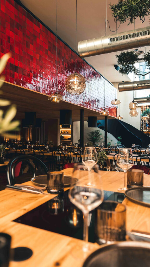 Stijlvol ingerichte tafels in ons restaurant in Sint Truiden met houten accenten en moderne hanglampen.