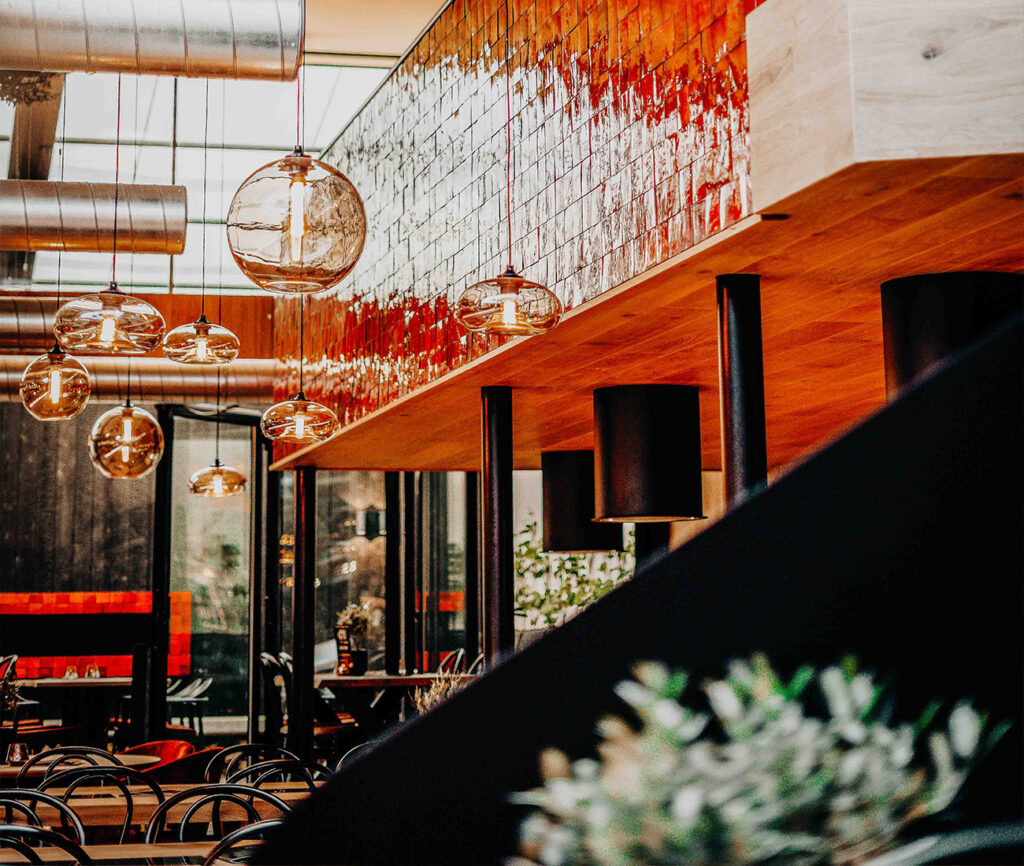Modern interieur van ons fondue restaurant in Sint-Truiden met hangende bolvormige lampen en houten elementen.