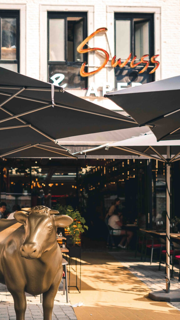 Zonnig Buitenterras van ons fondue restaurant met parasols en een gouden kalf