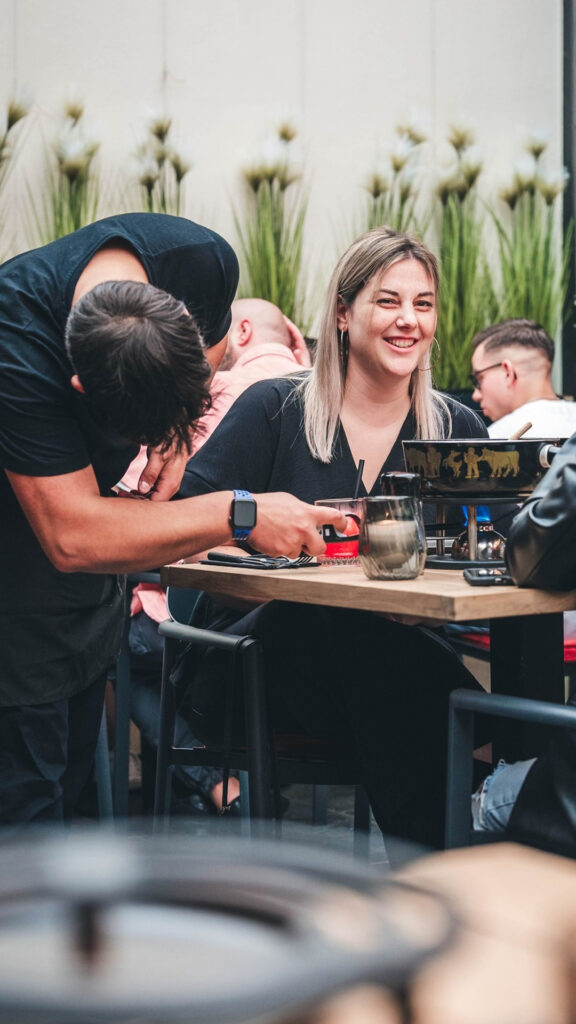 Glimlachende vrouw genietend van een fondue maaltijd aan een buiten tafel op ons gezellig terras.