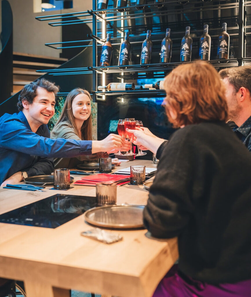 Vrienden die samen proosten rond een fonduepot in ons levendig restaurant.